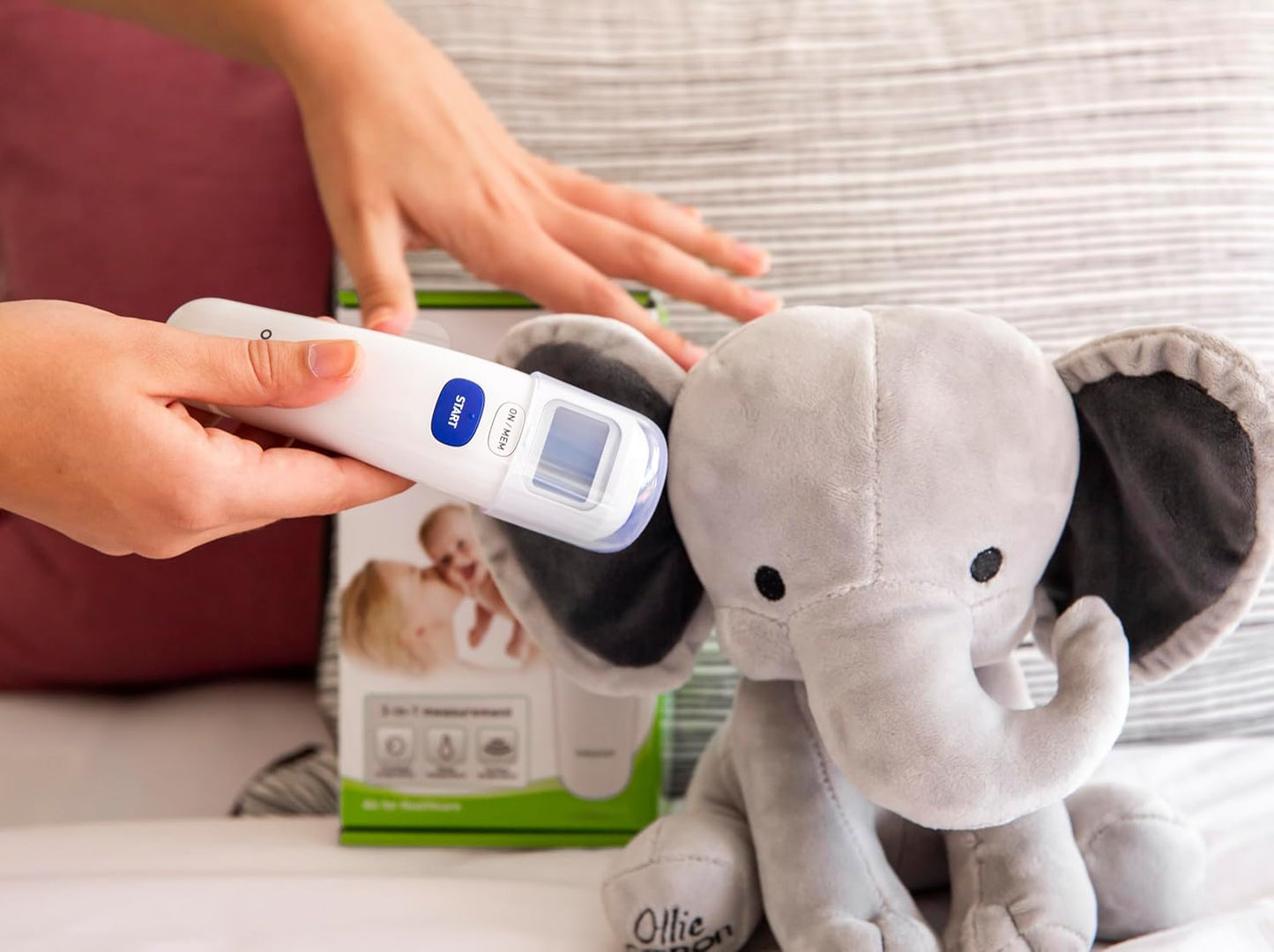 Hand holding Omron forehead thermometer for quick temperature check