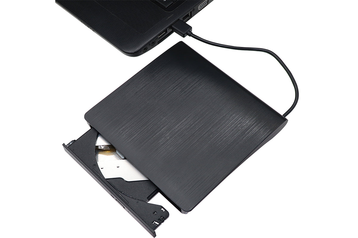 External DVD drive resting on wooden desk with laptop nearby