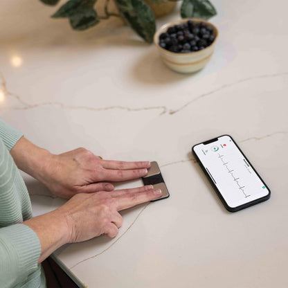 User placing fingers on KardiaMobile ECG sensors for heart check