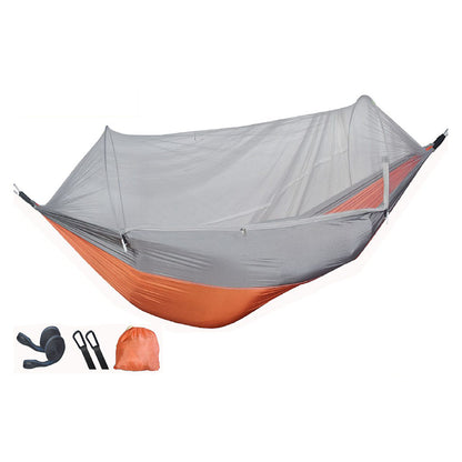 Outdoor camping hammock in orange grey nylon fabric hanging between trees